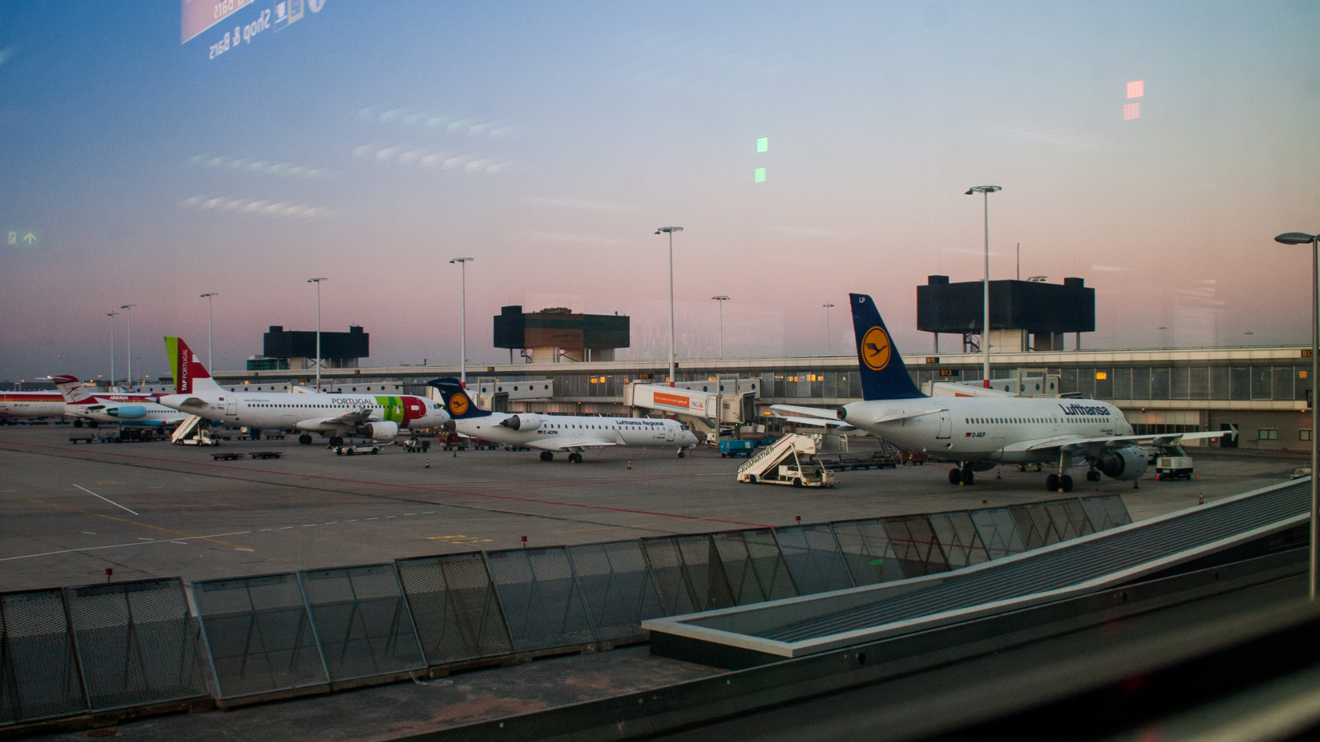Aeroporto al tramonto, aerei ai gate, luci della pista.