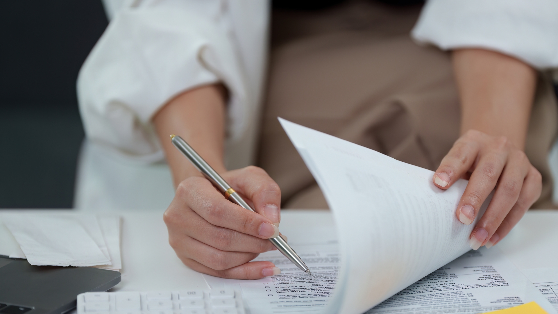 在专业的工作环境中，一个人在用笔审阅法律文件，桌上有键盘和文件。.